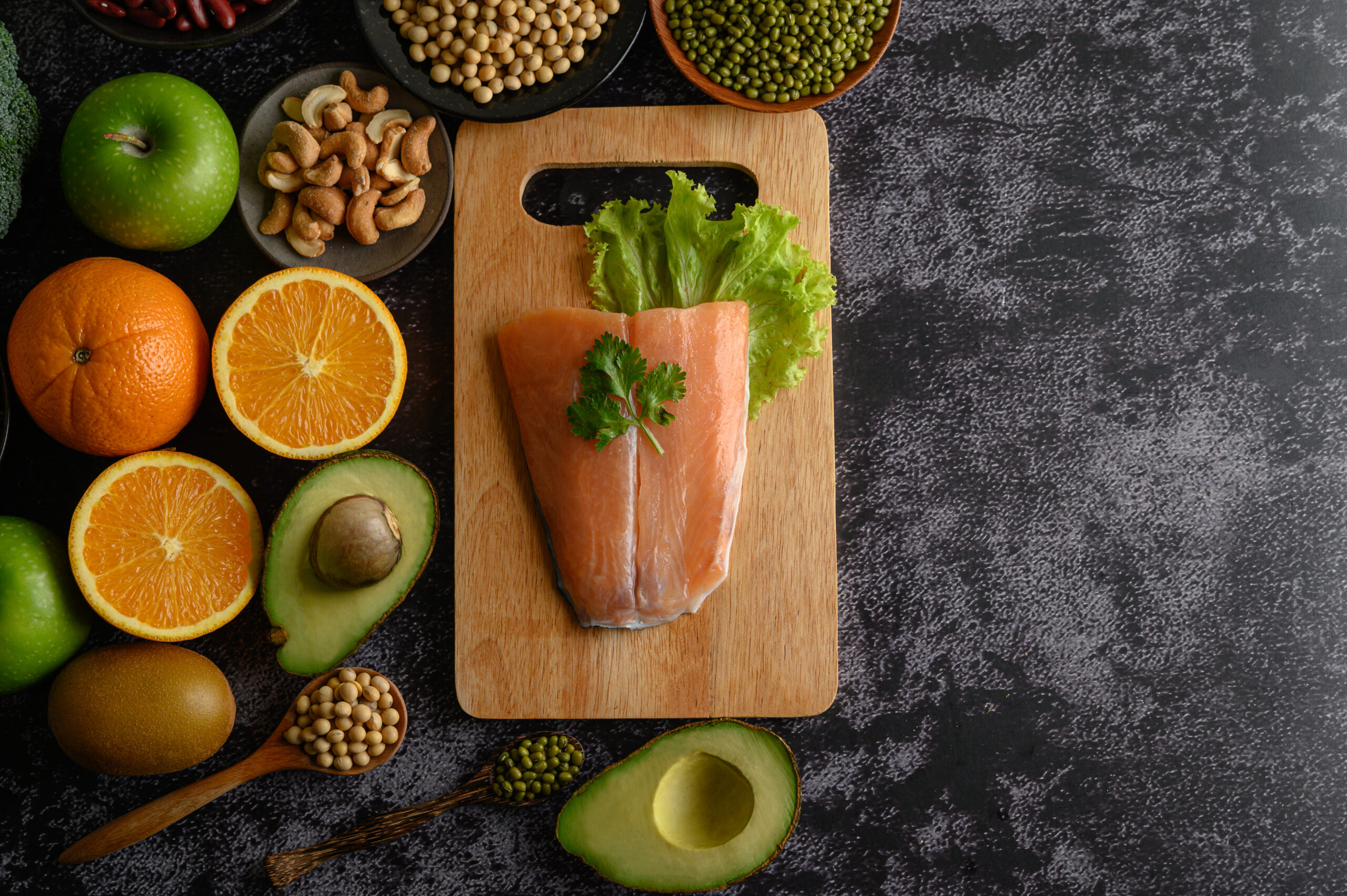 legumes, fruit, and Salmon fish pieces on a wooden chopping boar